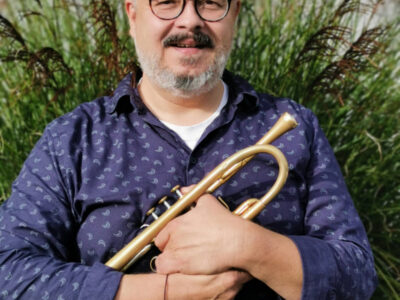 Mann mit Trompete. Musiker mit Brille und Bart. Musikinstrument im Freien.