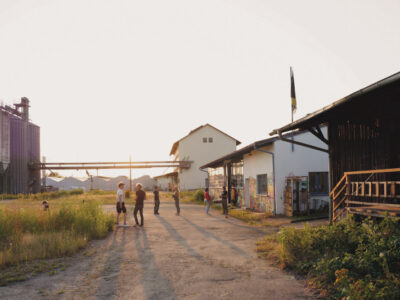 Industriegebiet mit Gebäuden, Silos und Personen. Ländliche Szene im Freien.