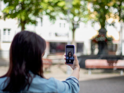 Frau macht Selfie mit Smartphone im Park. Reisen und Technologie.