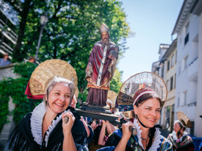 Frauen in Tracht tragen Statue bei Prozession. Traditioneller Brauch, Fest.