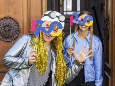 Zwei feiernde Frauen mit Partybrillen, die die Zahl 1700 darstellen. Event, Jubiläum.