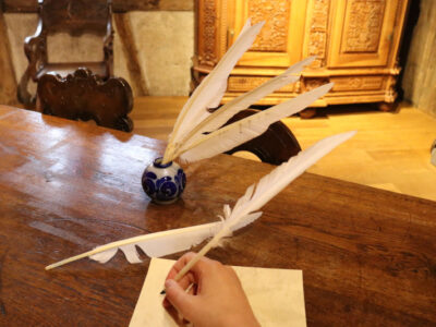 Federkiel und Tinte auf antikem Schreibtisch. Schreiben mit Feder, alte Schrift, historisch.